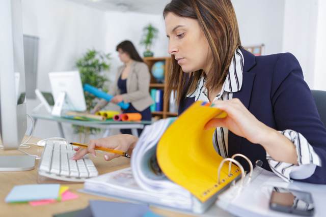 young businesswoman looking through a stack of PKLD2FN min